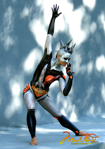 Woman in a metallic paint with spiked hair and an image of a rocket ship taking off on her torso